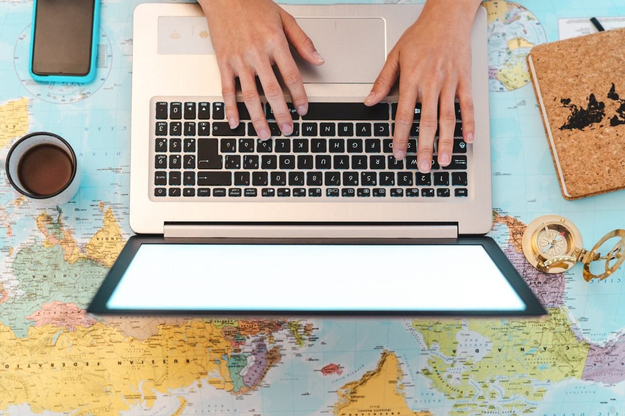 top-view-female-hands-using-laptop-on-world-map-booking-next-travel-destinations.